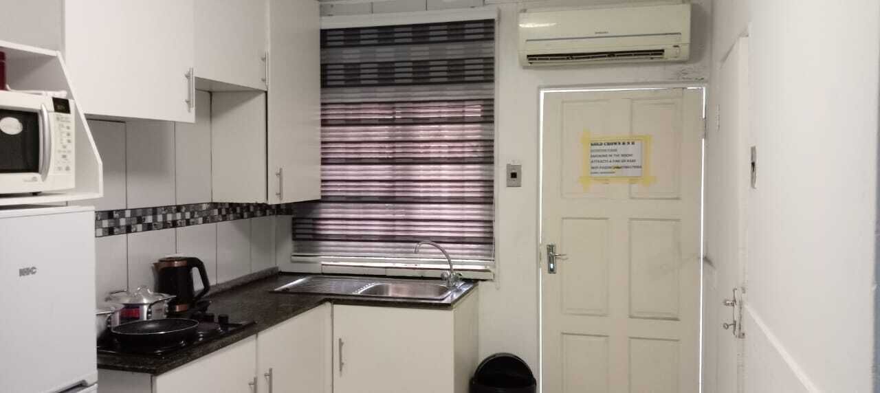 A compact kitchen with a microwave, kettle, and sink.