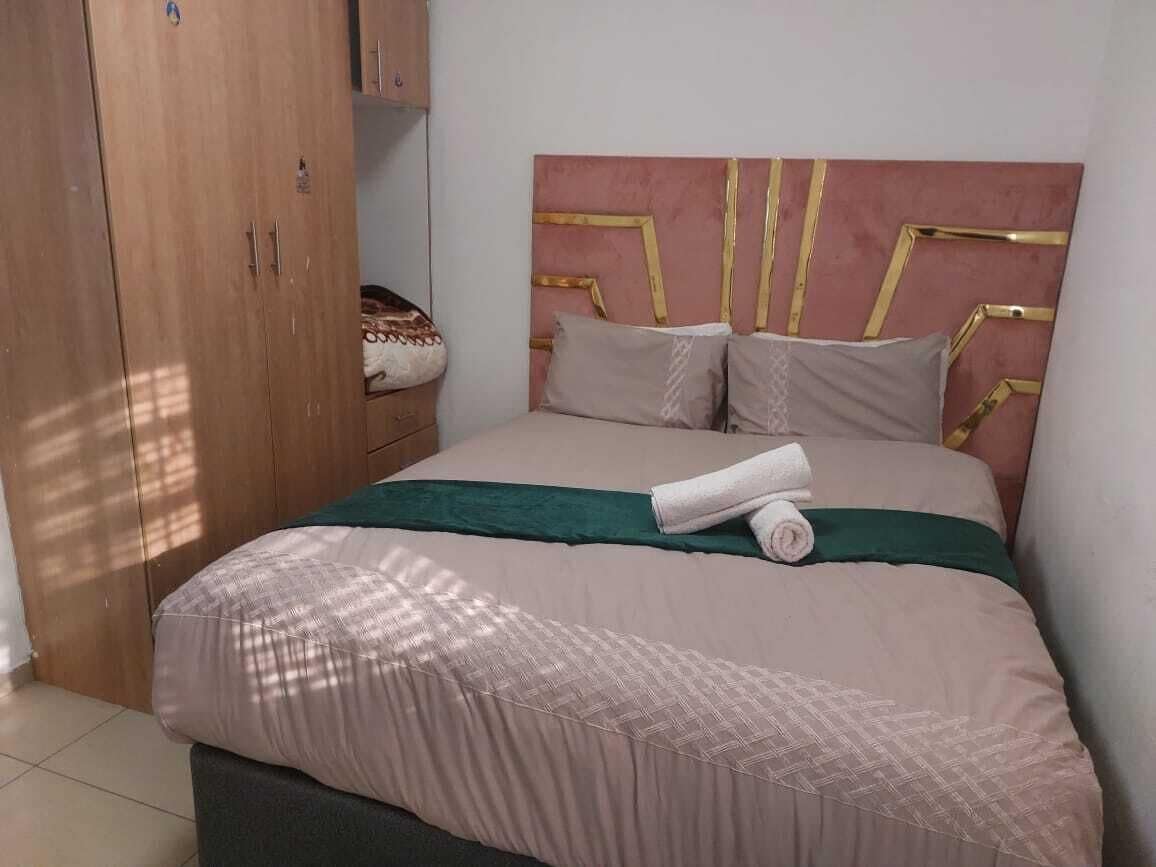 A bedroom with a bed, a wardrobe, and a headboard with a geometric design.