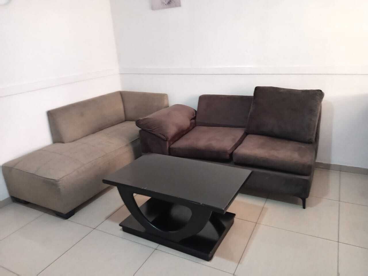 A corner seating area with a brown sofa, a brown armchair, and a black coffee table.