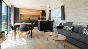 Eine moderne Küche mit Holzausstattung, ein Essbereich mit Tisch und Stühlen sowie ein Wohnbereich mit Sofa und Zierkissen.