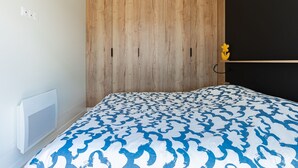 Ein Schlafzimmer mit einem hölzernen Kopfende, einem Heizkörper und einer geblümten Bettdecke.