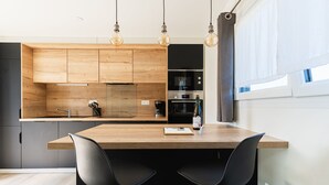 Eine moderne Küche mit Holzausstattung, einer zentralen Kochinsel mit zwei schwarzen Stühlen und Pendelleuchten.