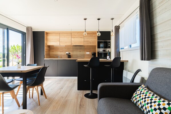 A modern kitchen with wooden cabinets, a bar area, and a dining space with a table and chairs.