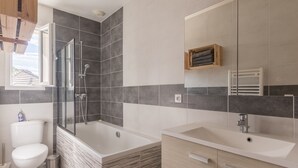 A modern bathroom with a shower, toilet, and sink.