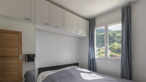 A bedroom with a bed, a wardrobe, and a window with curtains.