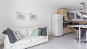 A modern kitchen with a white refrigerator, wooden cabinets, and a bar area with stools.