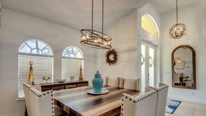 A dining area with a wooden table, upholstered chairs, and pendant lighting. - Villa Latitude Adjustment - Spacious 4 BR/ 3 bath waterfront Villa with heated pool and spa, kayaks and bikes (Cape Coral)