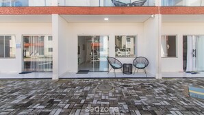Een modern gebouw met een hal met klinkers, glazen deuren en een zitgedeelte met stoelen.