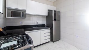 Een moderne keuken met witte kasten, een roestvrijstalen koelkast, een magnetron en een gasfornuis.