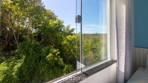Een kamer met een groot raam dat uitkijkt op een weelderig groen landschap.