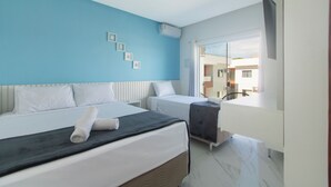 A hotel room with two beds, a blue accent wall, a large window, and a view of the outside.