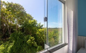 A room with a large window overlooking a lush green landscape. - Stay With Pool Just Minutes From the Beach - CCR (Porto Seguro)