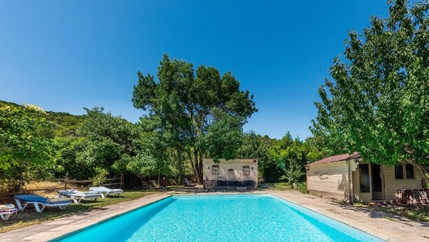 A rectangular swimming pool with a clear blue surface, surrounded by lounge chairs and a small building with a red roof. - La Bouscarle - Jardin et Piscine Partagée (Châteaudouble)