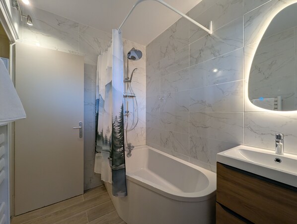 Un baño moderno con ducha, bañera, lavamanos y espejo.