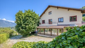 Ein zweistöckiges Haus mit Balkon, überdachter Terrasse und Bergblick.