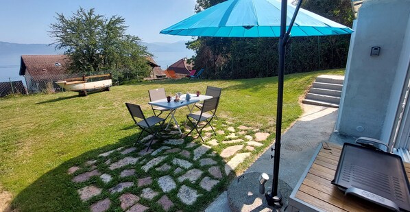 A patio with a table and chairs, a grill, and a view of the lake.