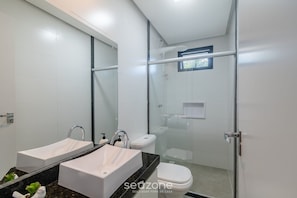A modern bathroom with a glass shower enclosure, a toilet, and a double sink with a black countertop. - Apartments With Swimming Pool 700m From Taperapuan Beach Nvm0009 (Porto Seguro)
