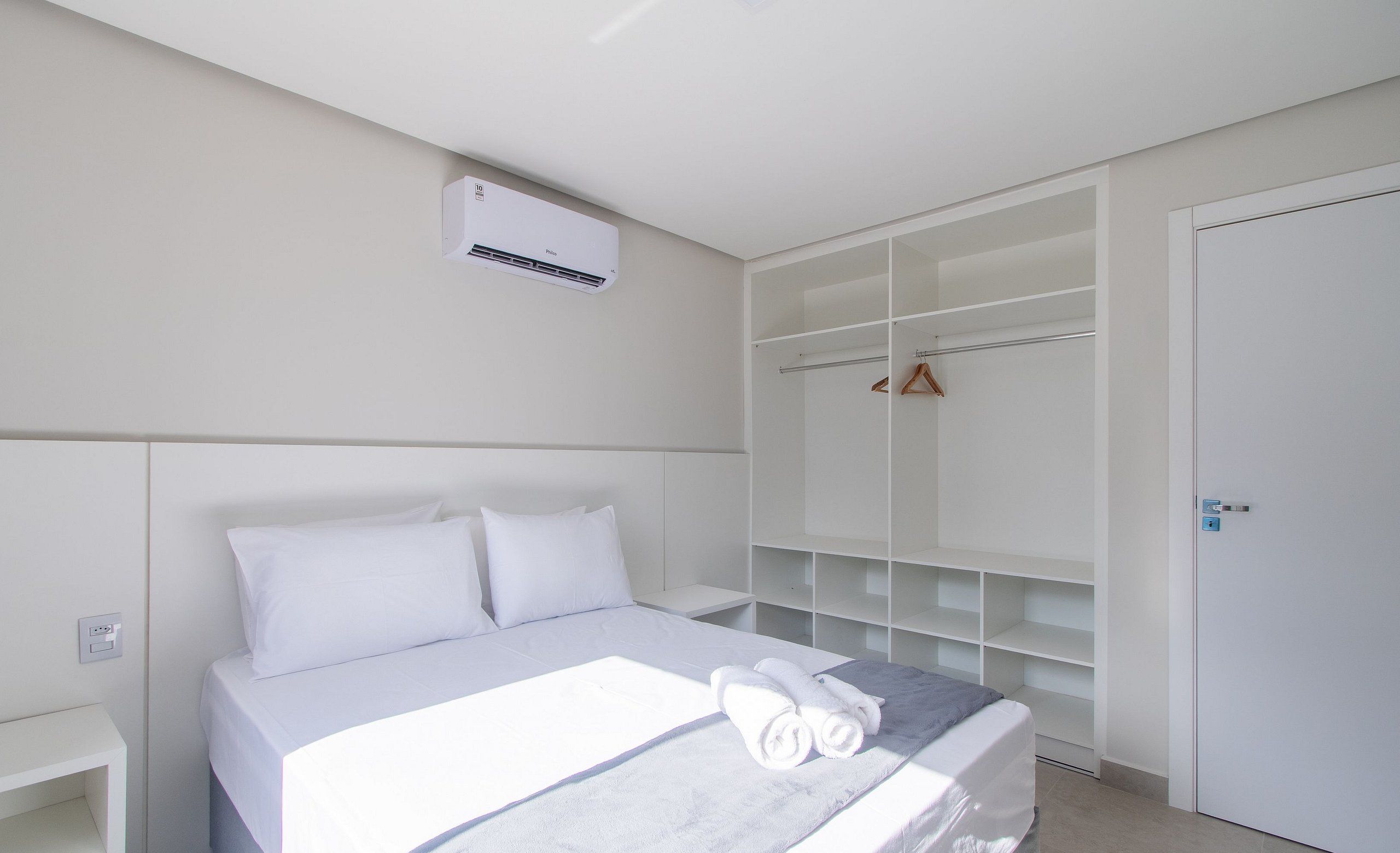 A bedroom with a bed, a wardrobe, and an air conditioning unit.