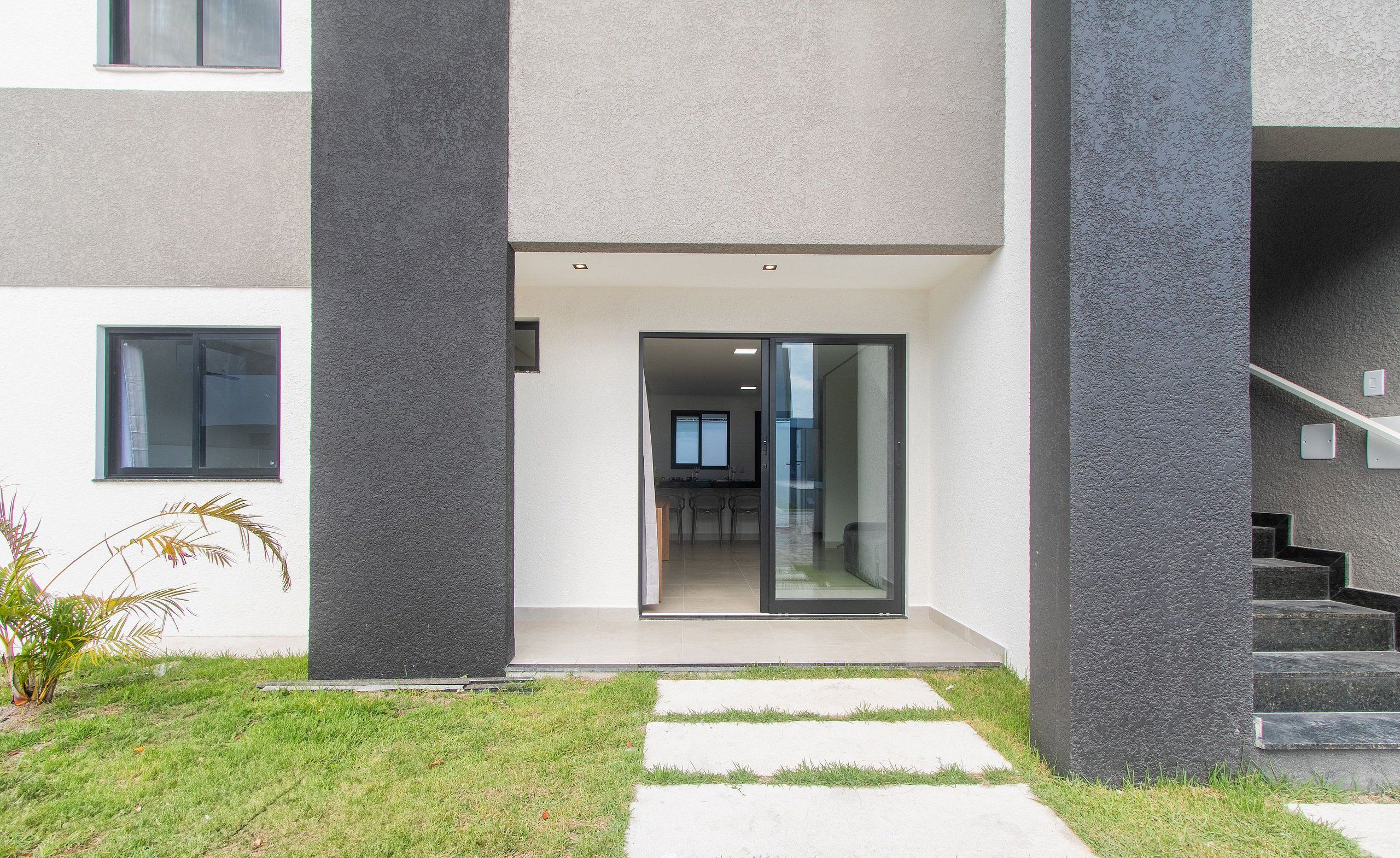 Een modern gebouw met glazen entree, een zichtbare keuken en een trap naar een hoger niveau.