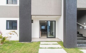 Un edificio moderno con entrada de vidrio, una cocina a la vista y una escalera que conduce a un nivel superior.