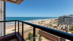 A balcony with a view of the beach, ocean, and adjacent buildings. - Beachfront Building With Pool - CPK (Ilhéus)