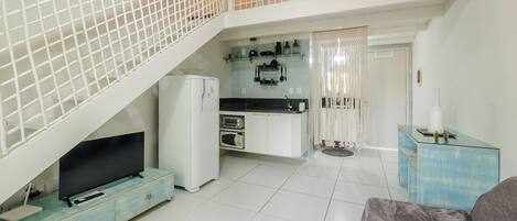 A compact living space with a kitchenette, a flat-screen TV, and a dining area.