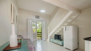 Een moderne woonkamer met een bank, een televisie, een koelkast en een trap.
