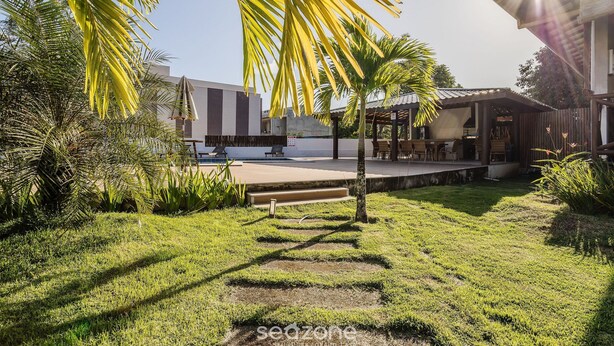 A well-maintained garden with a clear pathway, palm trees, and a pool area. - House With a Pool 5 Minutes From the Beach Cmv004 (Maraú)