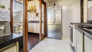 A kitchen with a stainless steel refrigerator, a stove, and a wooden door leading to a balcony. - House With a Pool 5 Minutes From the Beach Cmv004 (Maraú)