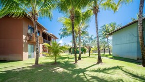 A courtyard with palm trees, a building with balconies, and a clear blue sky.