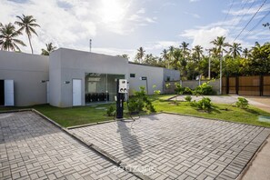 A modern building with a paved driveway and a charging station. - NLU - Full-featured Condominium at Marceneiro Beach (Passo de Camaragibe)