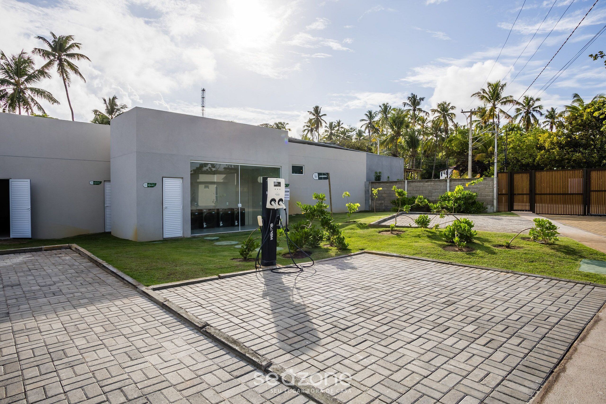 Un edificio moderno con entrada pavimentada y estación de carga.