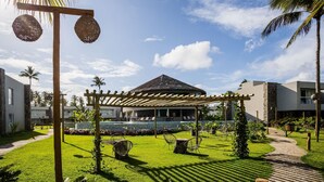 A resort with a thatched-roof structure, a covered outdoor seating area, and a well-maintained lawn. - NLU - Full-featured Condominium at Marceneiro Beach (Passo de Camaragibe)