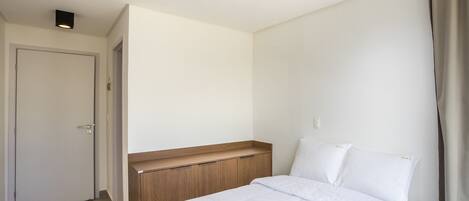 A bedroom with a bed, a wooden headboard, a white door, and a light fixture on the ceiling.