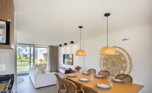 A modern dining area with a wooden table set for six, surrounded by wicker chairs. - NLU - Full-featured Condominium at Marceneiro Beach (Passo de Camaragibe)