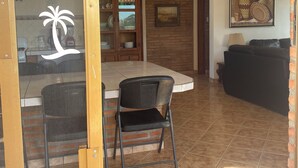 A dining area with a brick wall, a wooden cabinet, and a painting. - Casitas Las Palmas (Punta de Mita)