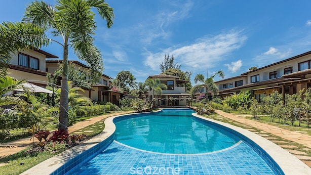 A swimming pool surrounded by palm trees and a clear blue sky. - House With Pool in the Condominium Cvb0144 (Maraú)
