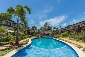 A swimming pool surrounded by palm trees and a clear blue sky. - House With Pool in the Condominium Cvb0144 (Maraú)