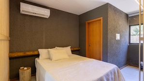Un dormitorio con cama, cabecera de madera, aire acondicionado y una puerta.