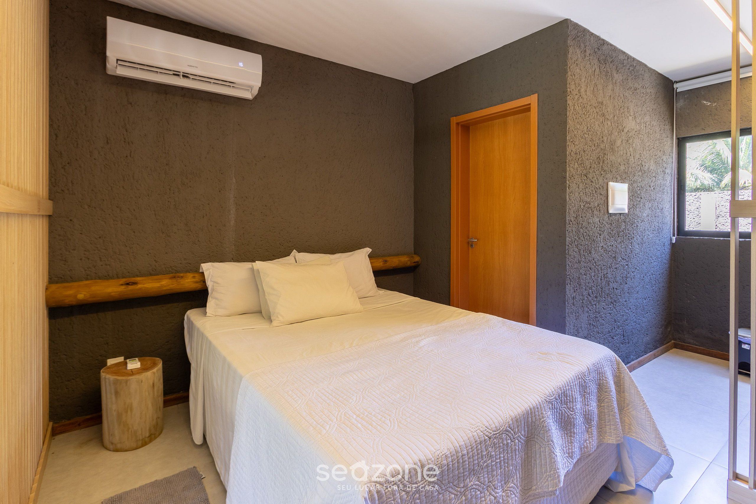 Een slaapkamer met een bed, een houten hoofdeinde, een airconditioning en een deur.