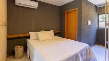 Een slaapkamer met een bed, een houten hoofdeinde, een airconditioning en een deur.