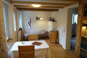 Una habitación pequeña y acogedora con una cama individual, un escritorio, una silla, una lámpara y una estantería con libros.