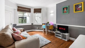 Uma sala de estar aconchegante com sofá, televisão e área de jantar com mesa e cadeiras.