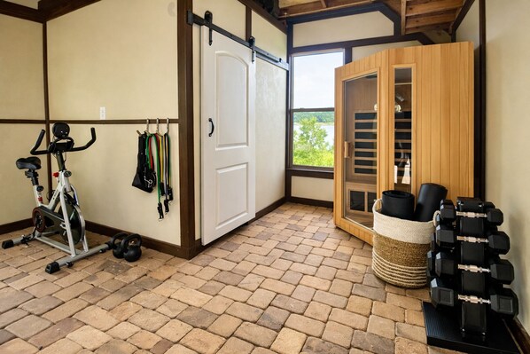 A room with a stationary bike, weights, and a sliding door leading to a balcony.