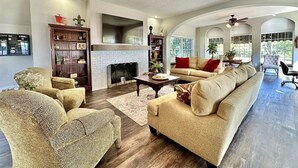 A spacious living room with a fireplace, a large sofa, a coffee table, and a ceiling fan.