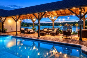 A poolside area with a covered seating area, a pool, and a view of a body of water.