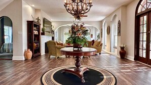 Un salon spacieux avec une table basse ronde, un lustre et une grande fenêtre.