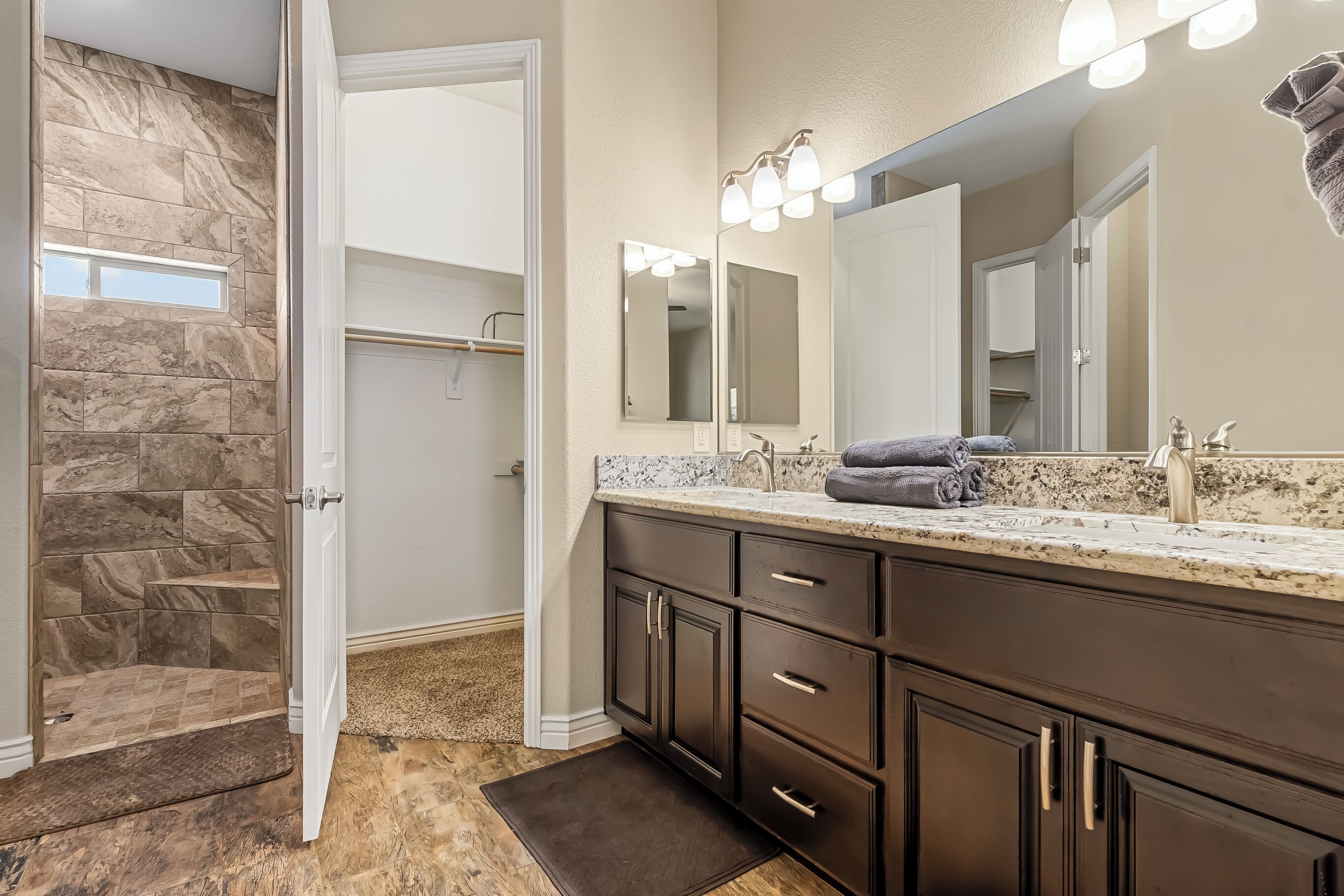 A bathroom with a marble vanity, a large mirror, and a shower area with a stone wall.