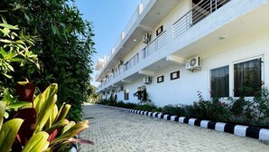 A multi-story building with balconies, air conditioning units, and a paved pathway. - Dreamland Resort (Kaladhungi)