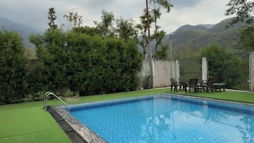 Piscina rectangular con zona verde alrededor y una valla.